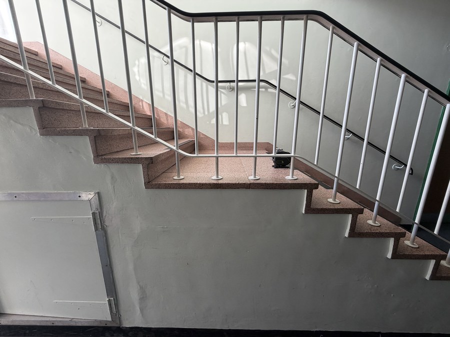 The original white painted steel bar balustrade on the same school staircase before replacement